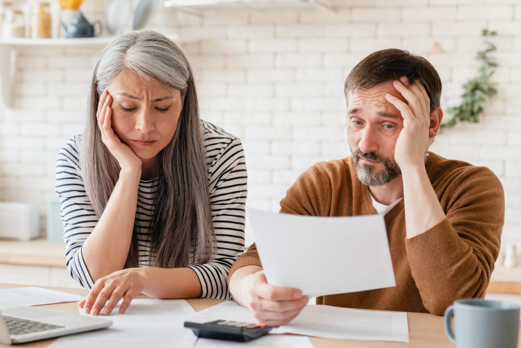 Sad disappointed mature middle-aged couple family wife and husband counting funds, savings